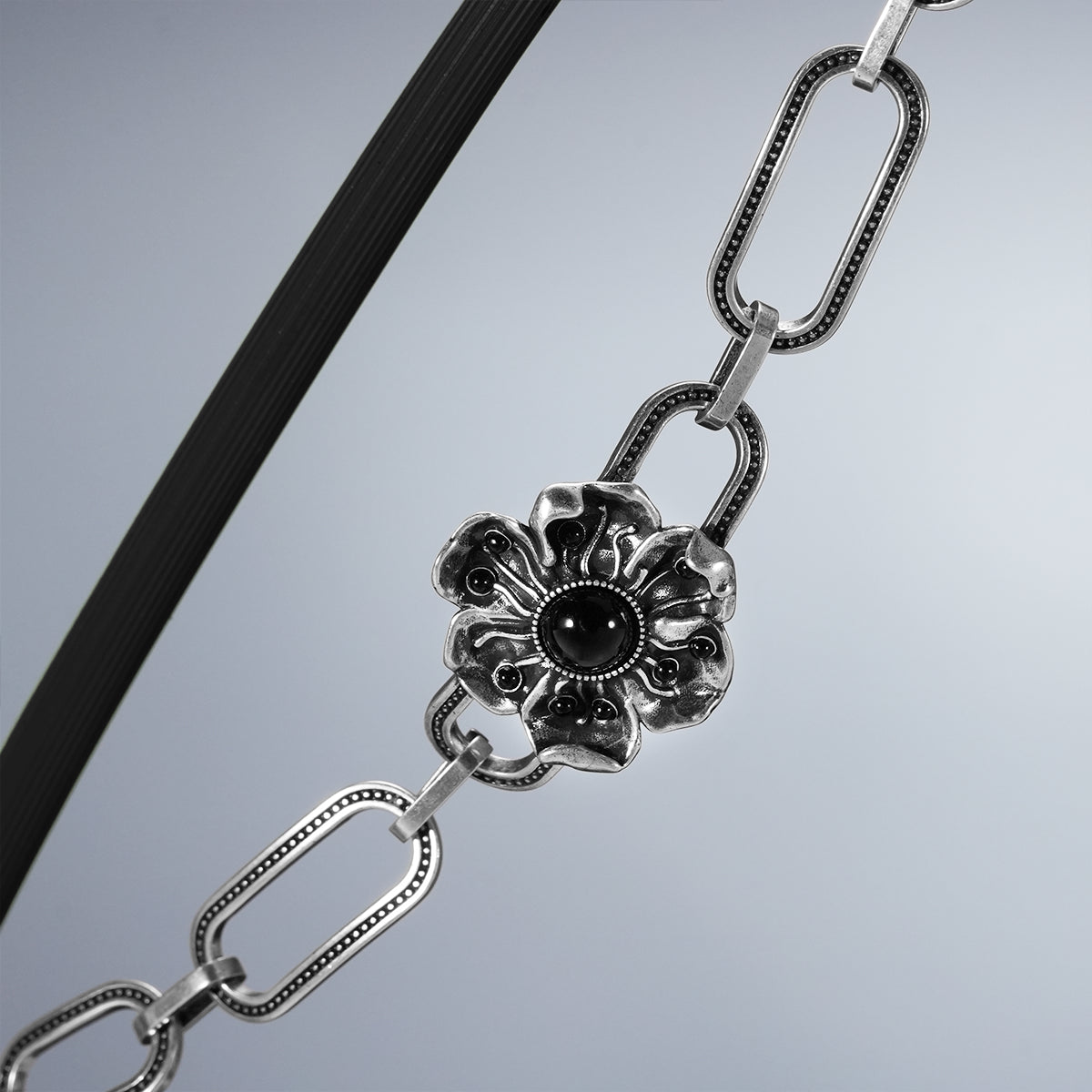 Close-up of silver Bound Bloom bracelet with black-centered flower clasp