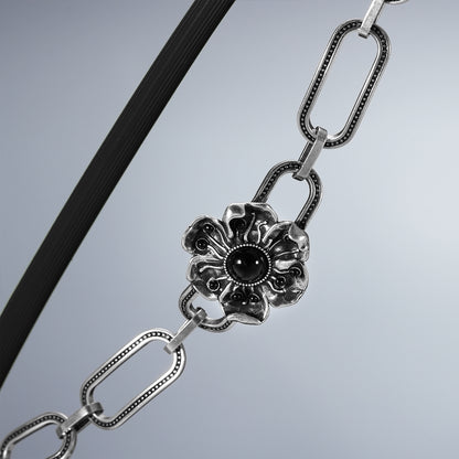 Close-up of silver Bound Bloom bracelet with black-centered flower clasp