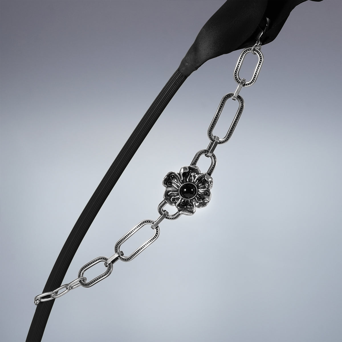 Silver Bound Bloom bracelet draped between two dark stems