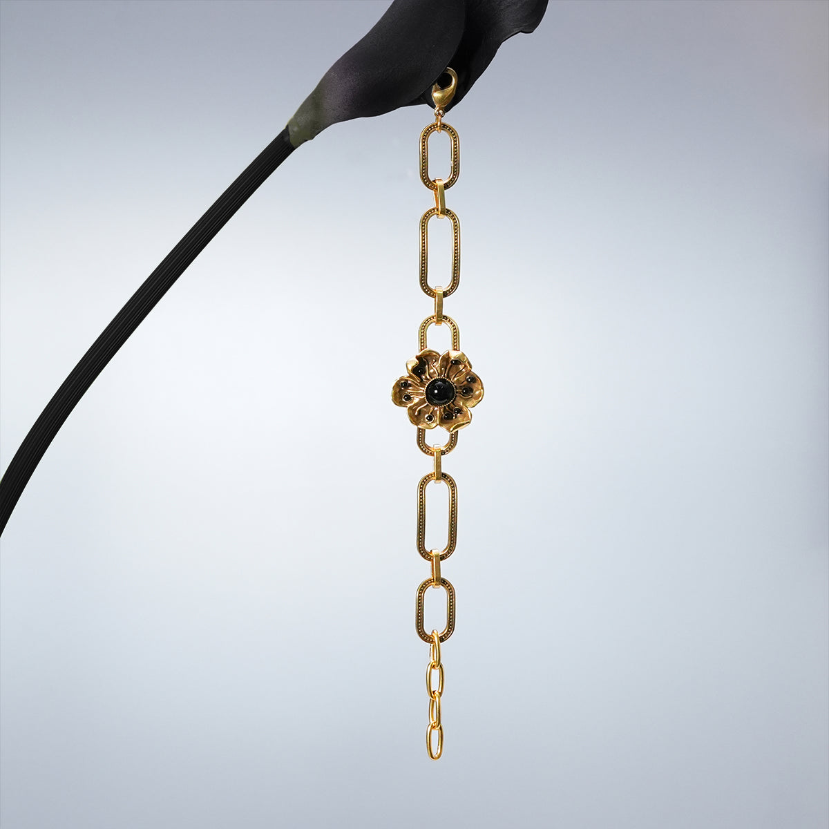 Gold Bound Bloom bracelet hanging vertically from a dark stem