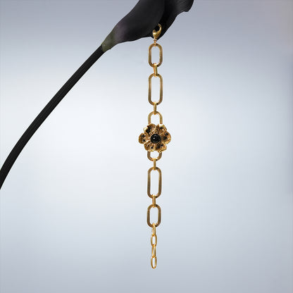 Gold Bound Bloom bracelet hanging vertically from a dark stem