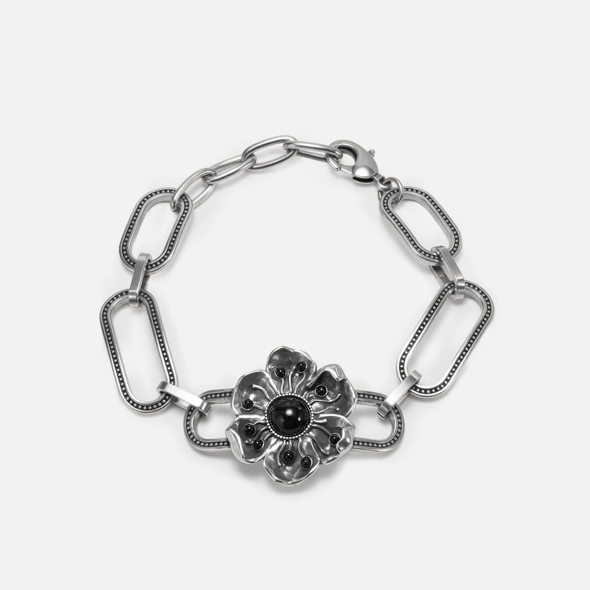 Silver-tone bracelet with paperclip chain links and a flower charm centered with a black stone