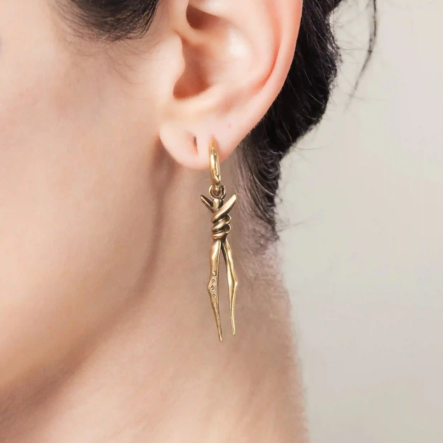 Model wearing gold Bound Twin Earrings with bound spike drops and hammered hoop detail