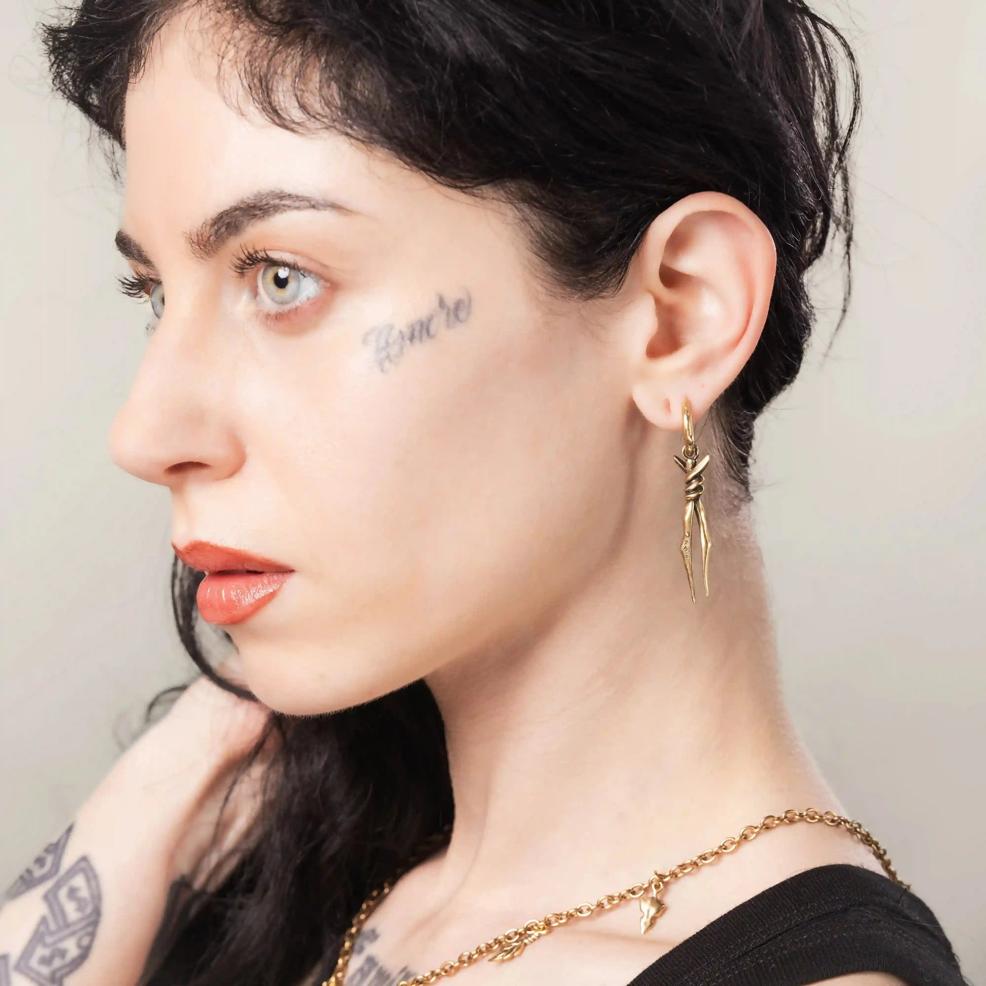 Gold Bound Twin Earrings styled on model with sharp ritual drop earring design