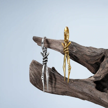 Bound Twin Earrings in silver and gold displayed on driftwood with dark woodland styling