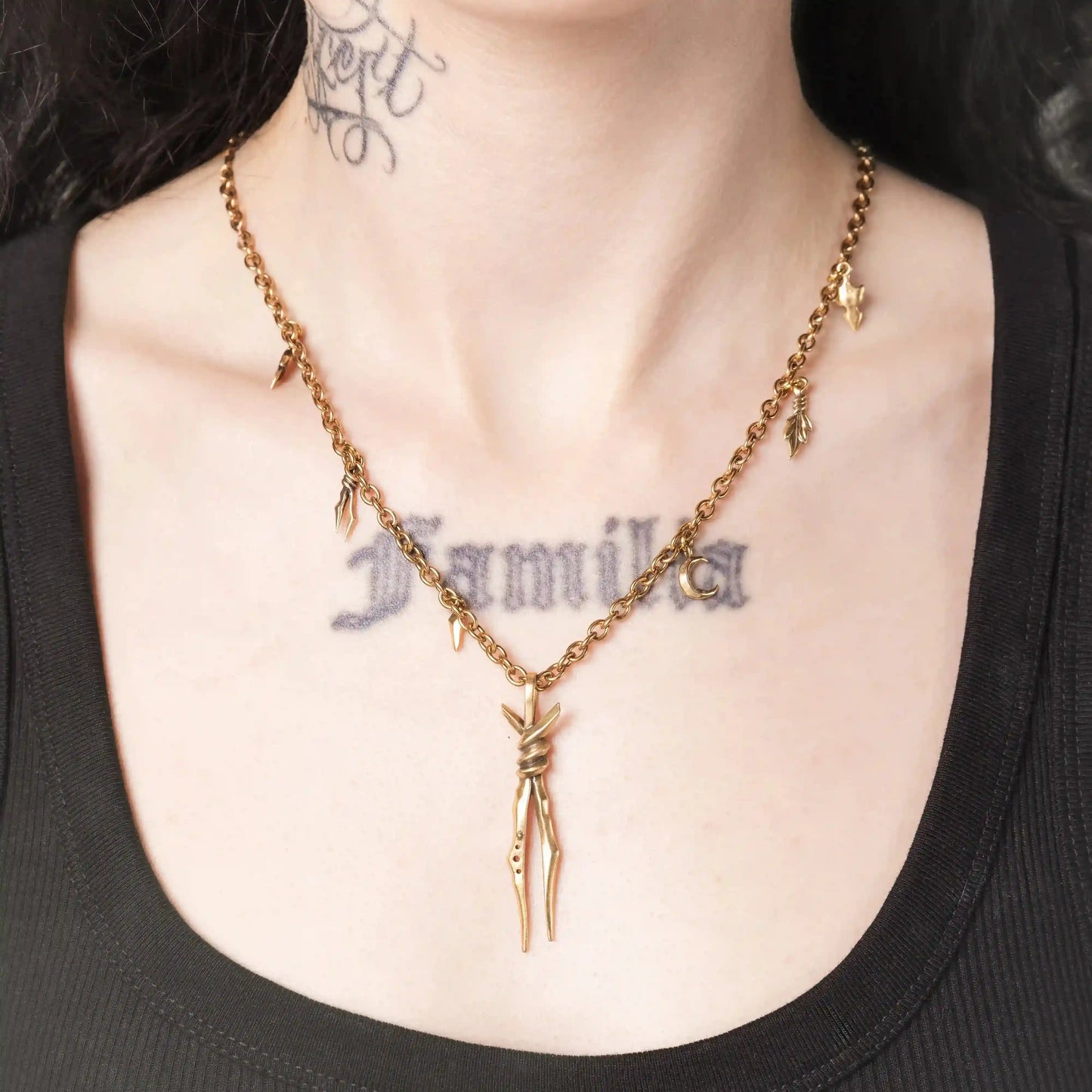 Model wearing the gold Bound Twin Necklace with long twin spike pendant and leaf charms