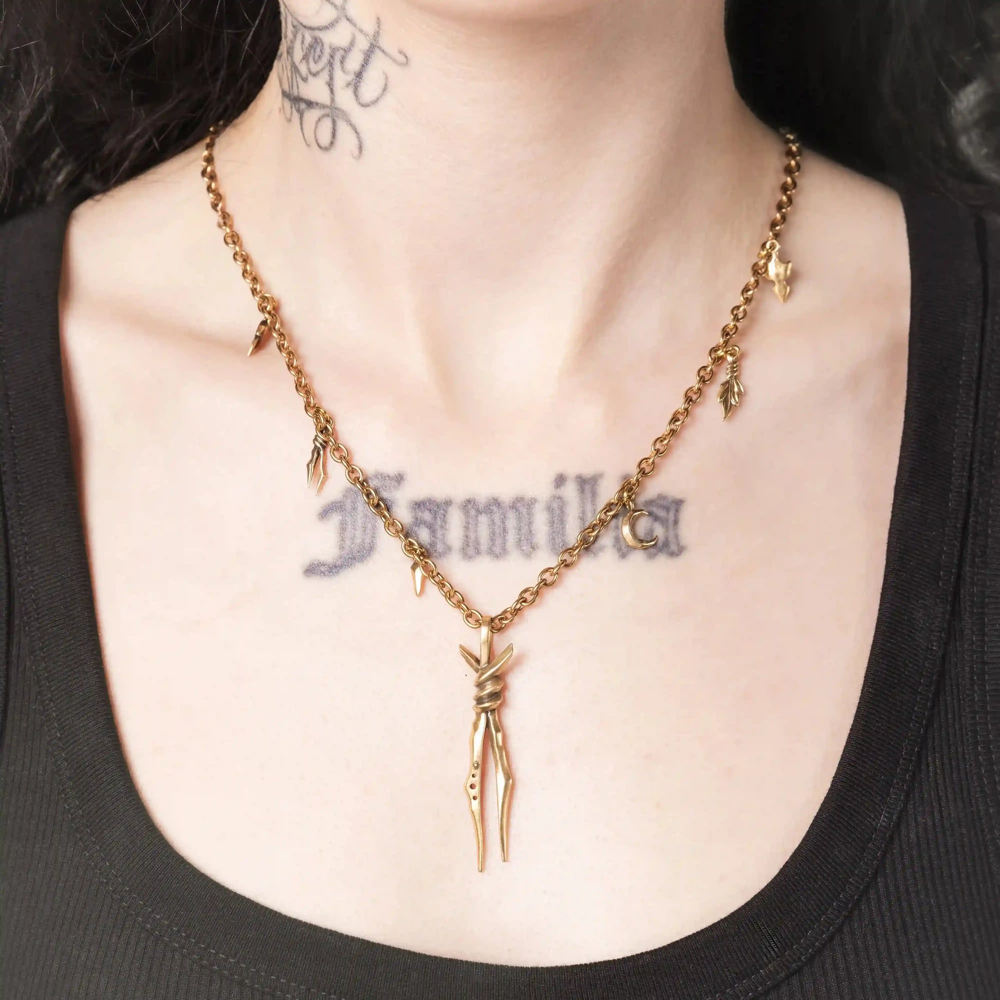 Model wearing the gold Bound Twin Necklace with long twin spike pendant and leaf charms
