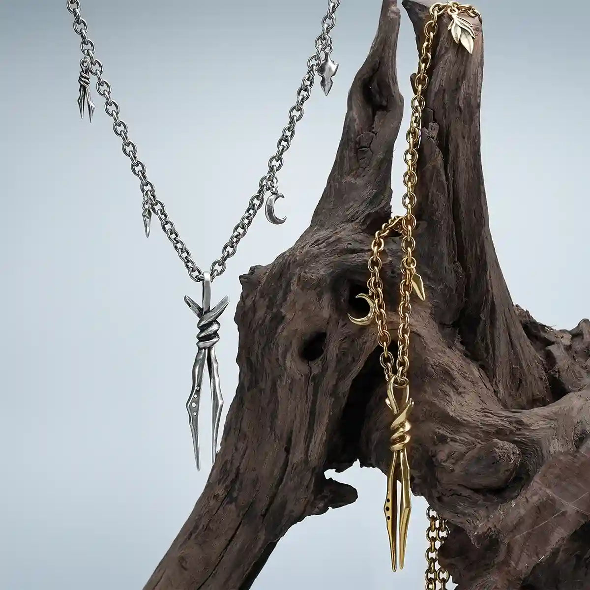 Bound Twin Necklace in gold and silver displayed on weathered wood with dark woodland styling