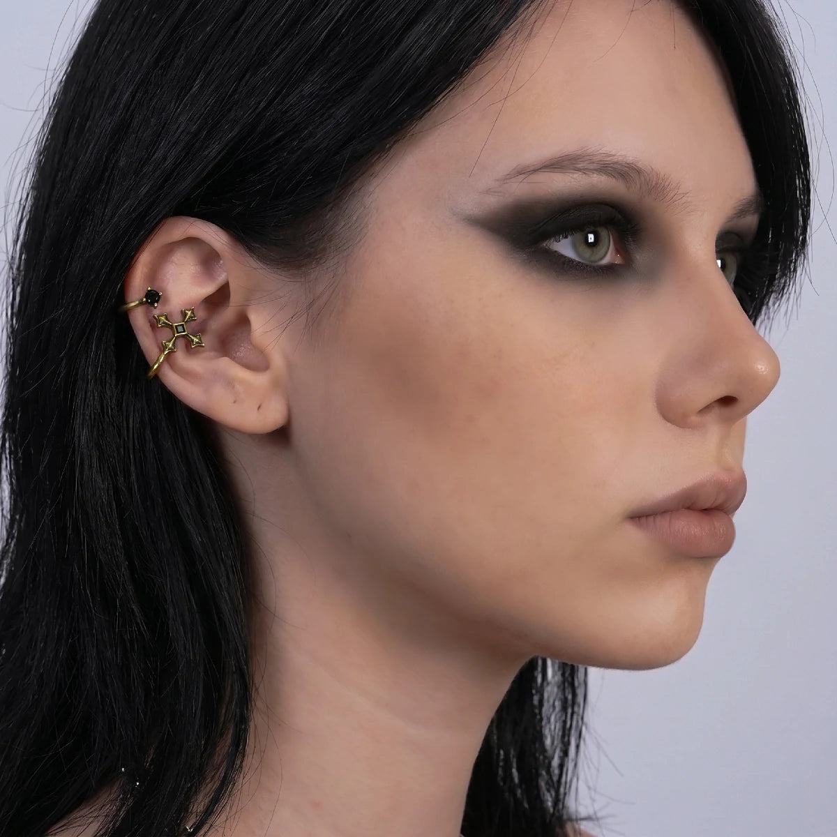 Bound Vestige Ear Cuffs in antiqued 18K gold worn on the upper ear in a side-profile portrait with dark hair.