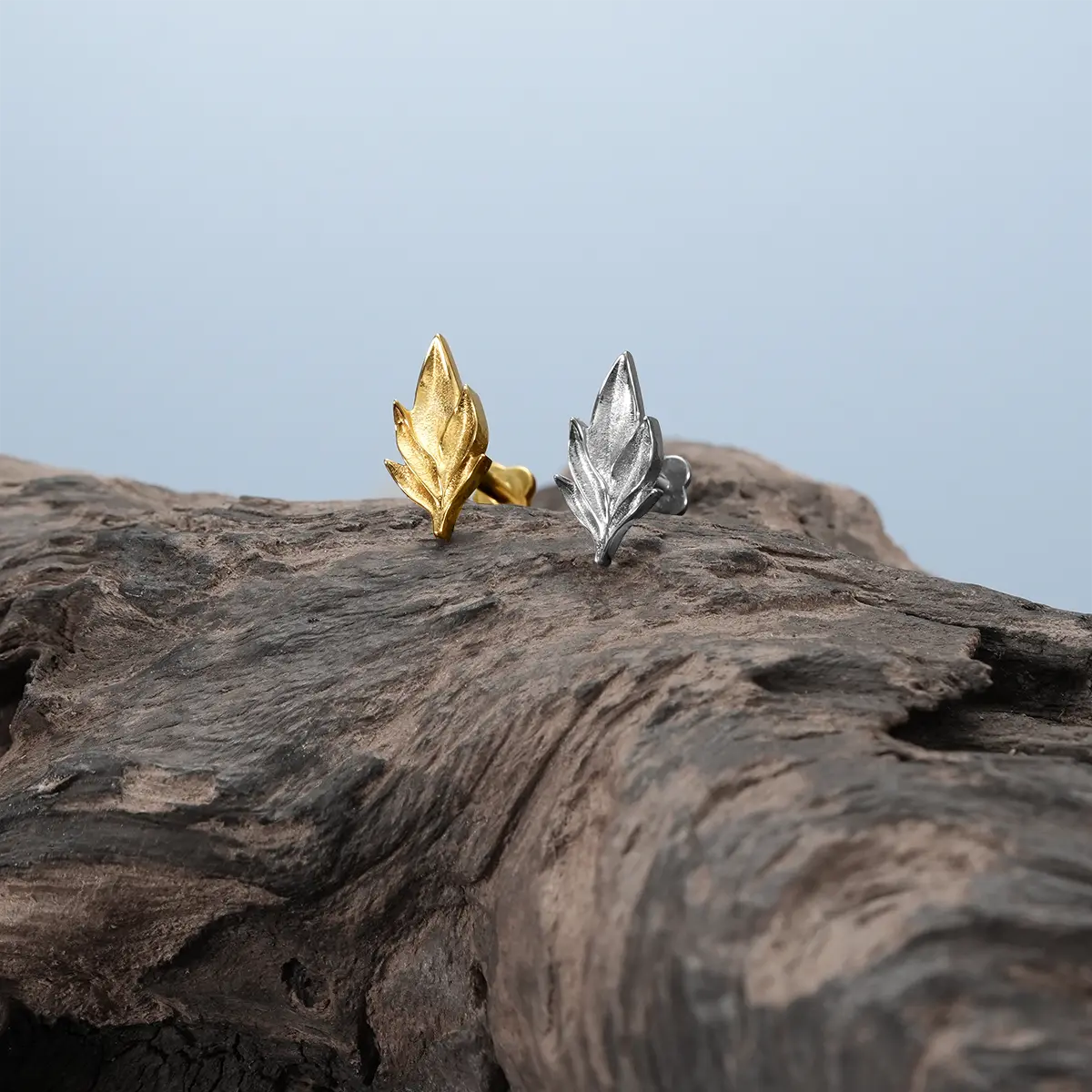 Bramble Leaf Ear Studs in gold and silver displayed on driftwood with botanical relic styling