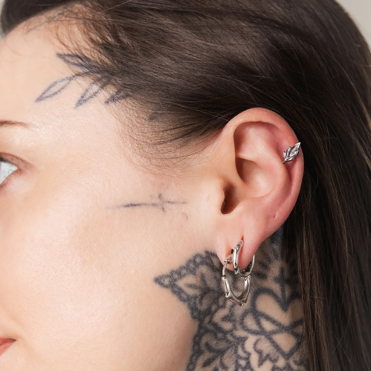 Model wearing silver Bramble Leaf Ear Studs with sharp botanical leaf detail