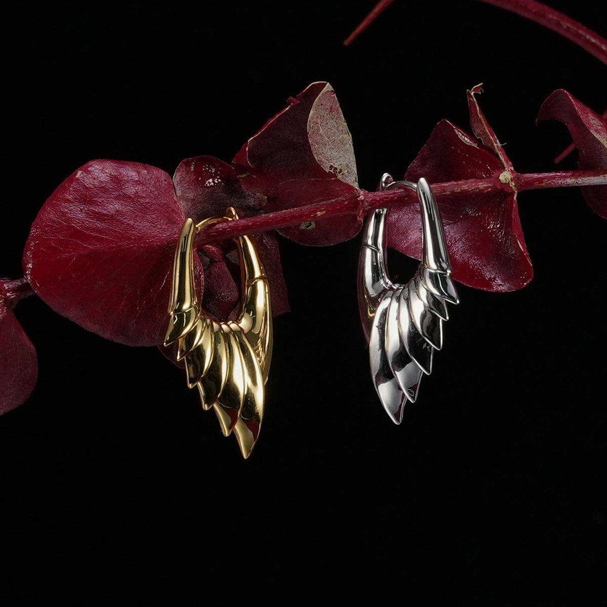 Gold and silver Carapace Wing hoop earrings hanging from red leaves