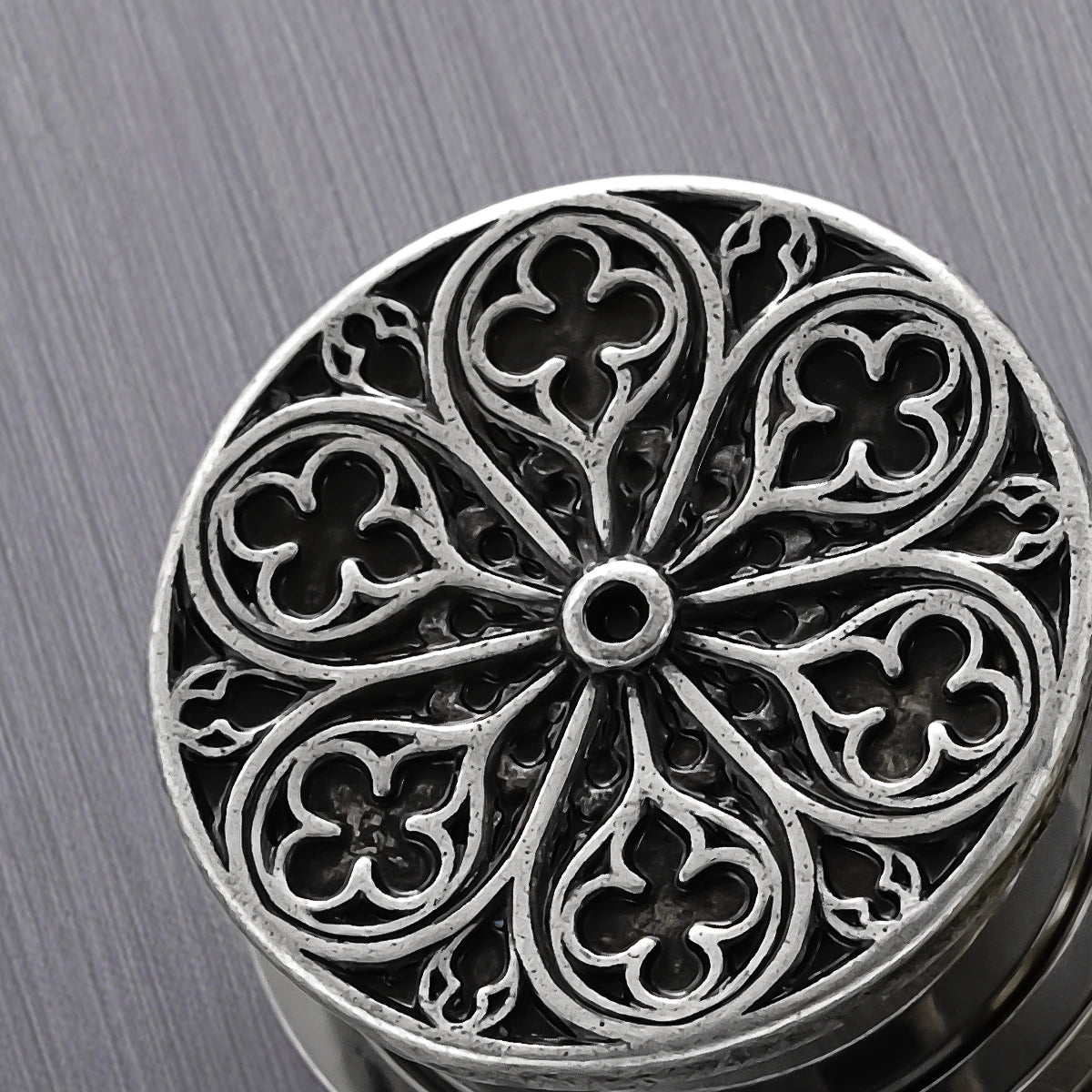 Close-up of silver Cathedral Rose plug with circular window tracery design