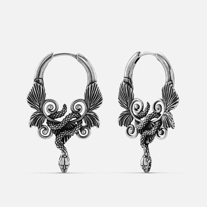 Pair of oxidized silver-tone hoop earrings with a serpent and wing motif, front view on a plain background