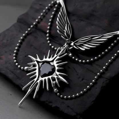 Close-up of a silver-tone Celestial Starburst Wings pendant with feathered wings and a black heart center