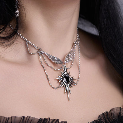 Silver-tone starburst wings necklace with black stone pendant worn on model's neck, close view