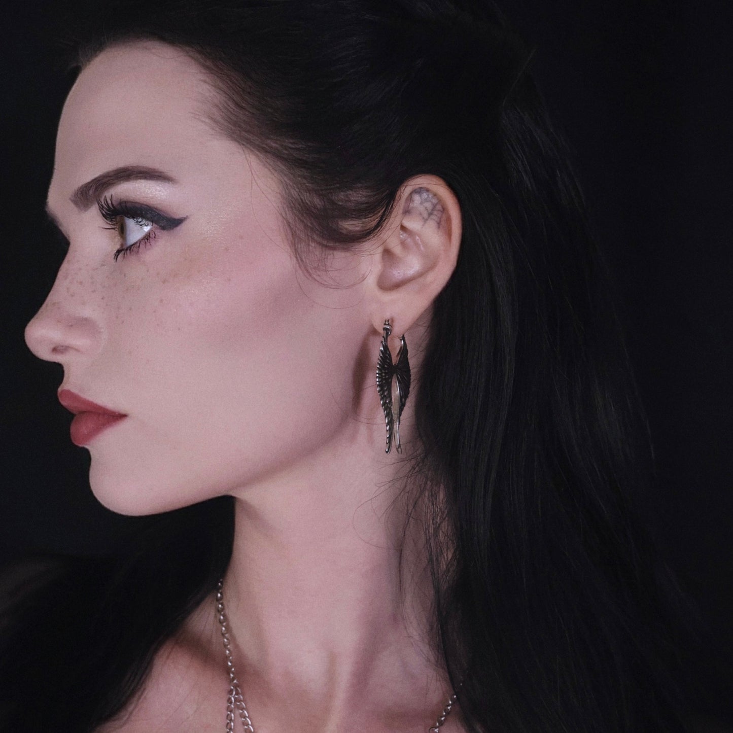 Model wearing a pair of long silver Celestial Wing earrings