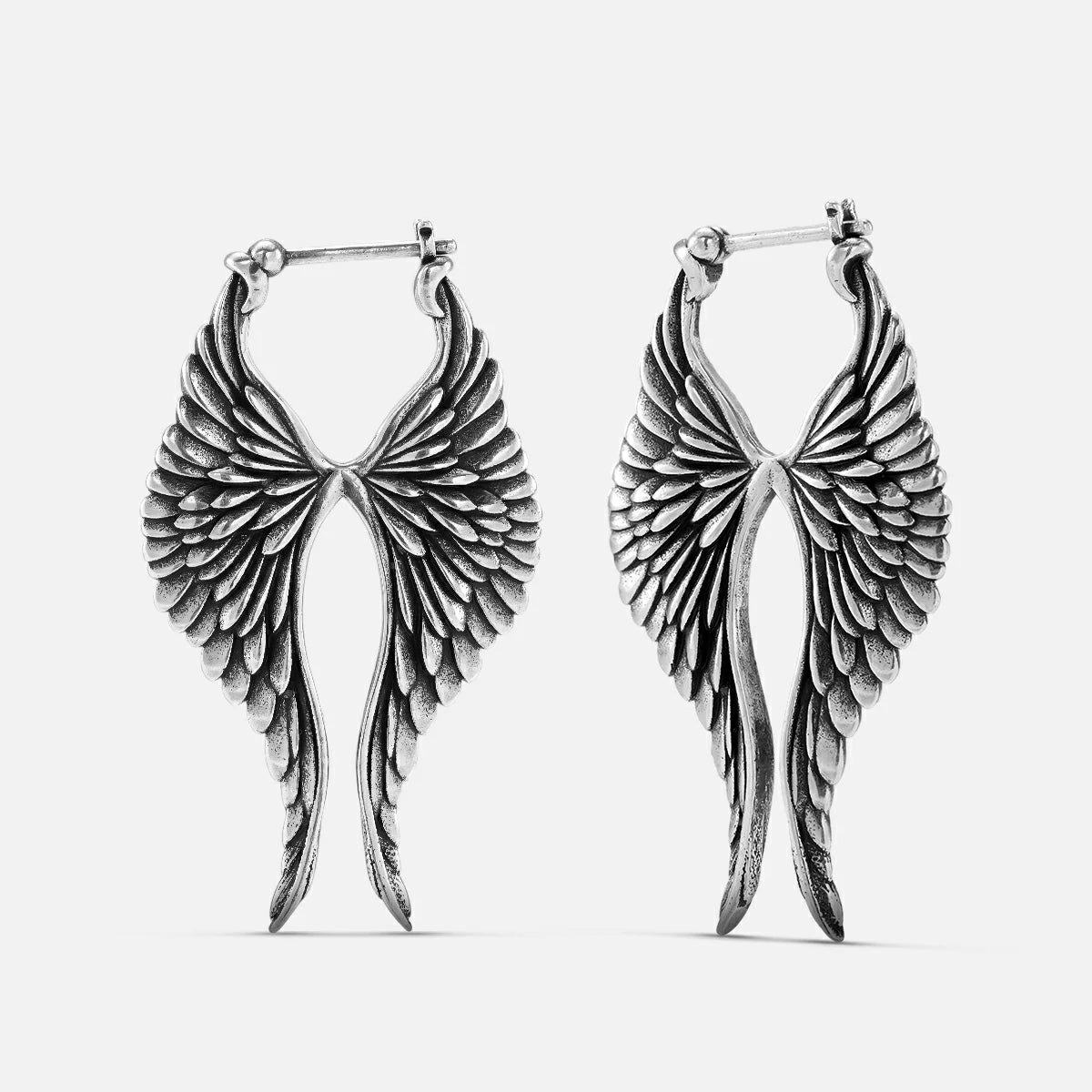 Pair of oxidized silver-tone celestial wing earrings with hoop closures shown against a white background
