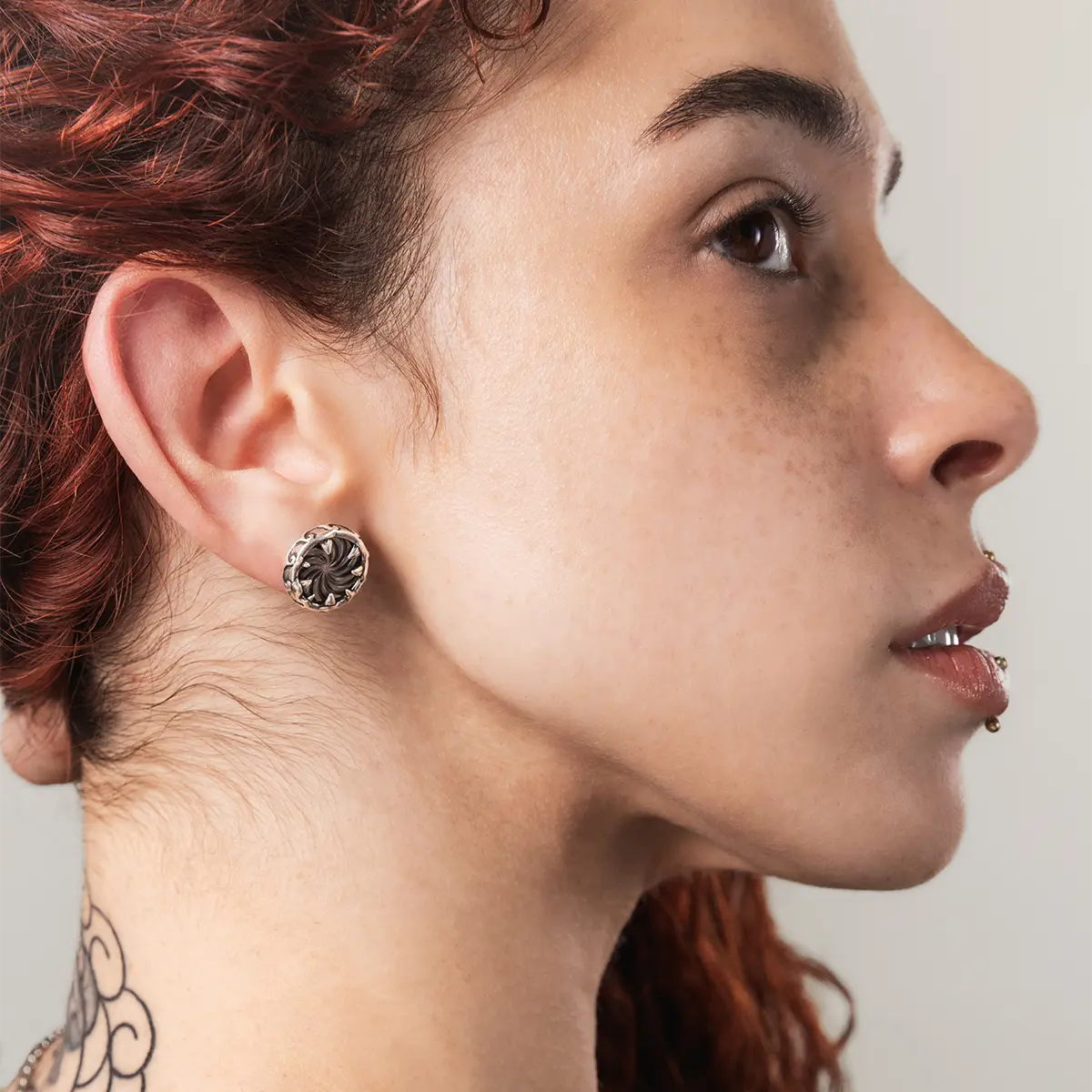 Model wearing Charybdis Maw gothic stud earrings with iridescent abalone shell detailing