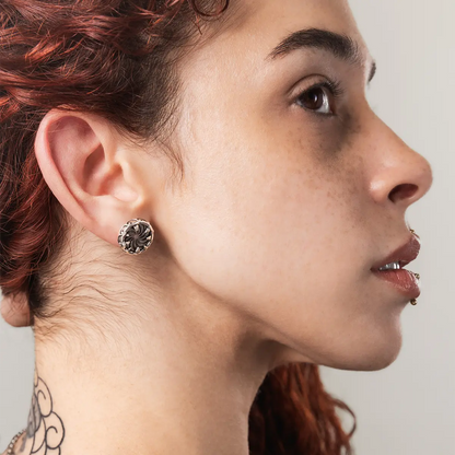 Model wearing Charybdis Maw gothic stud earrings with iridescent abalone shell detailing