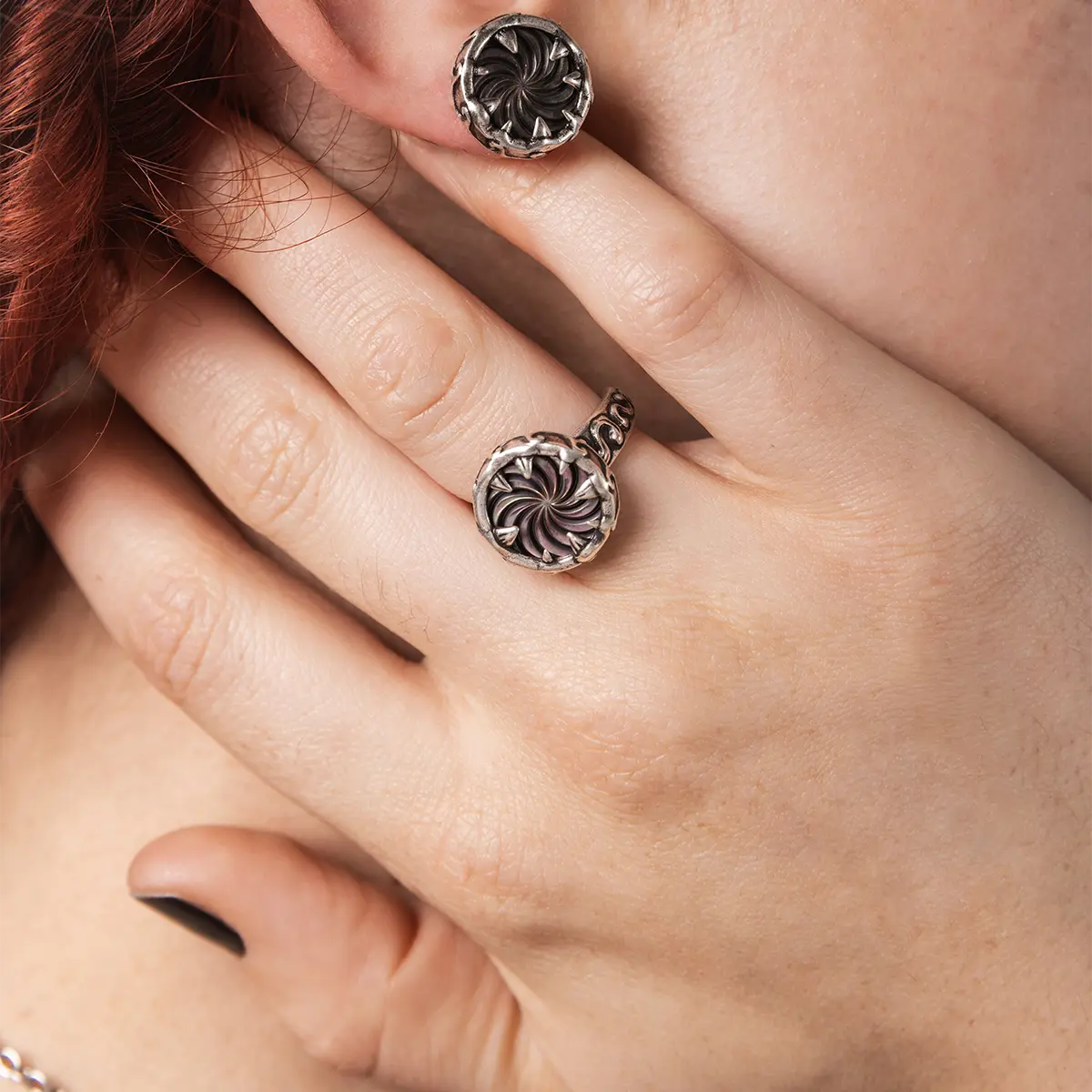 Model wearing the Charybdis Maw Ring with abalone shell center, showing the carved silver setting and bold gothic ring silhouette.