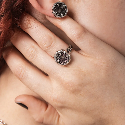 Model wearing the Charybdis Maw Ring with abalone shell center, showing the carved silver setting and bold gothic ring silhouette.