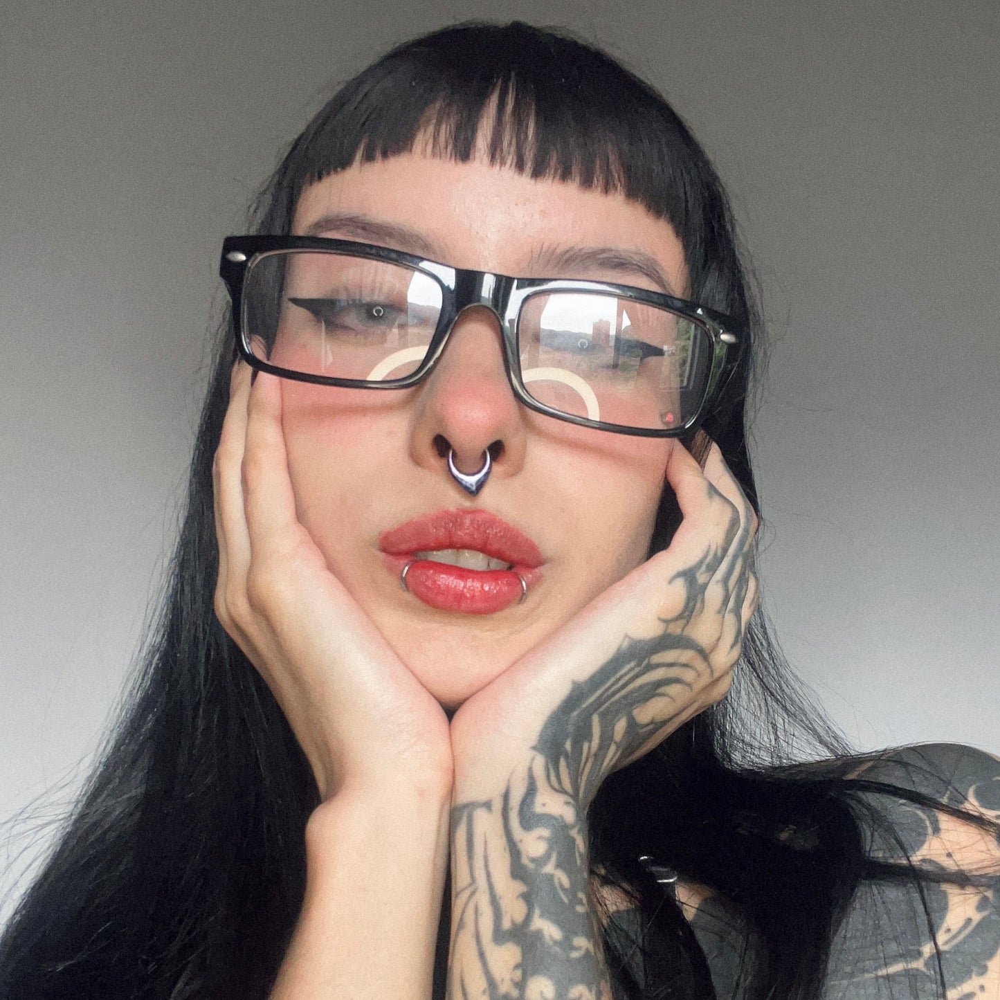 Model with glasses and dark hair wearing a septum ring with a swirled purple and blue finish