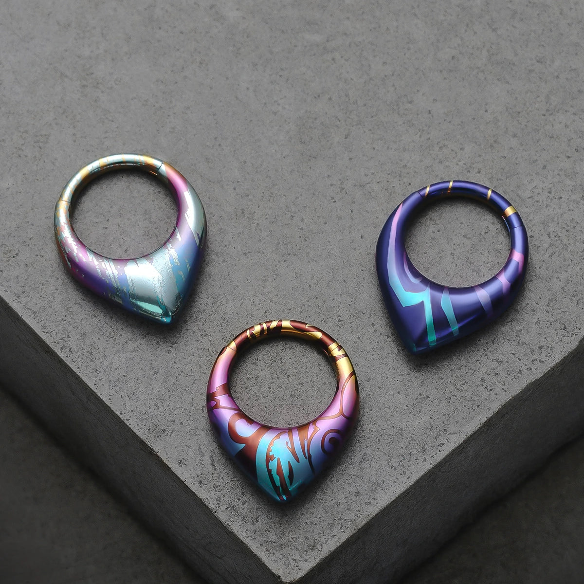 Three color patterns of Chroma Wave titanium clickers displayed on gray blocks