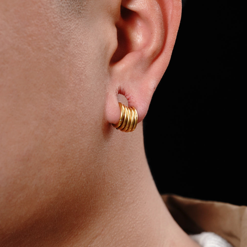 Close-up of a gold-tone stacked hoop earring worn in an ear, side view