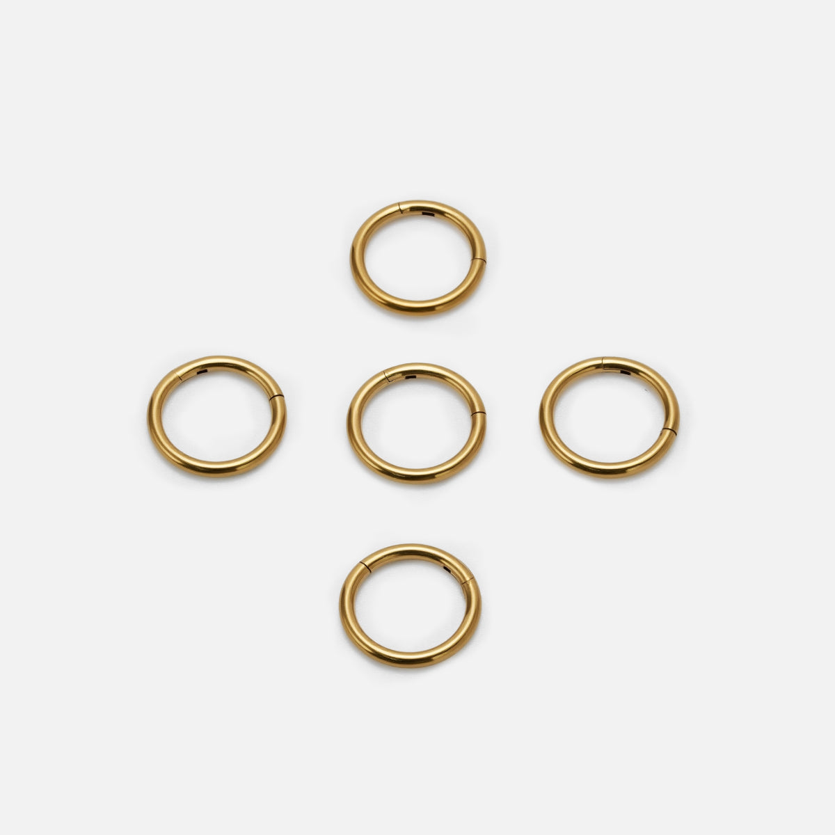 Five gold Chromatic Loop rings arranged on a white background