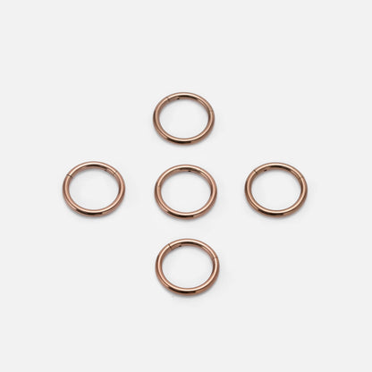 Five rose gold Chromatic Loop rings arranged on a white background