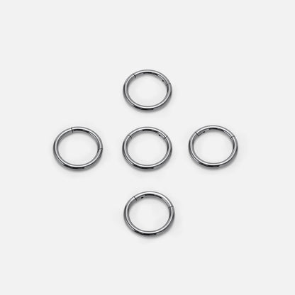 Five small silver-tone hoop earrings arranged in a diamond pattern on a flat surface