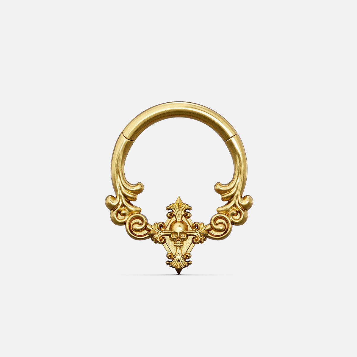 Gold-tone septum clicker ring with ornate scrollwork and a small skull motif, front view on white background