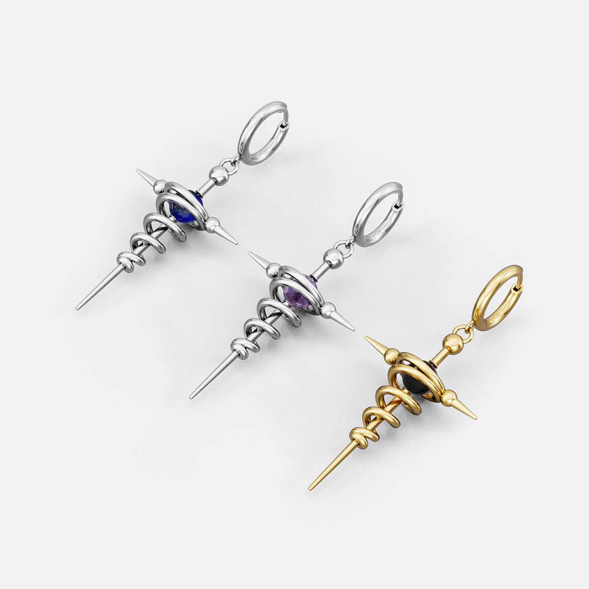 Three cosmic flow earrings laid flat, showing silver-tone and gold-tone spiral spike designs with colored bead accents