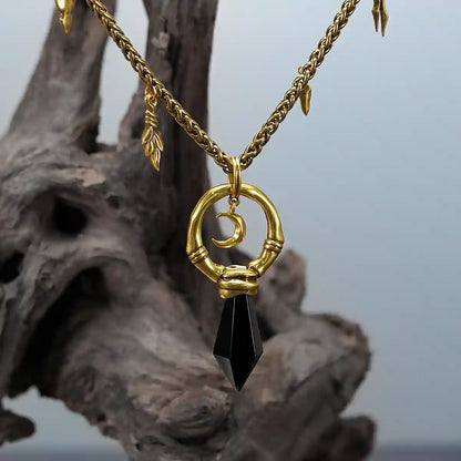 Close-up of gold Crescent Ward Necklace on weathered wood with black obsidian spike pendant