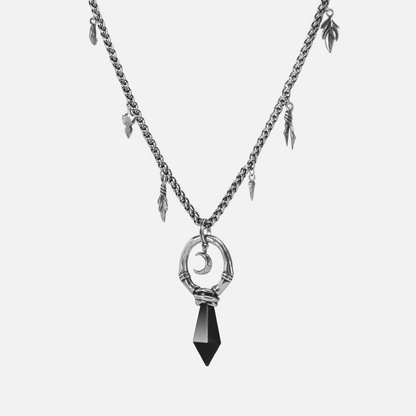 Close-up product view of the silver Crescent Ward Necklace, featuring a black obsidian spike, crescent moon charm, bone ring centerpiece, and relic-like chain accents.