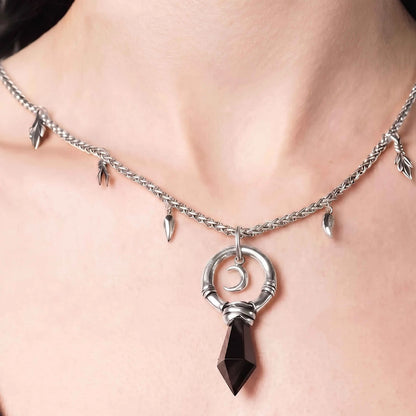 Model wearing the silver Crescent Ward Necklace with black obsidian spike pendant, crescent moon charm, and gothic forest-inspired chain details.