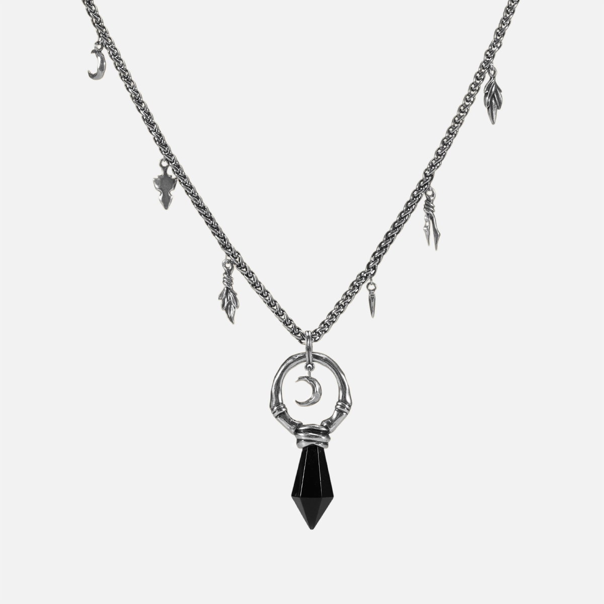 Silver Crescent Ward Necklace with black obsidian spike pendant, crescent moon charm, bone ring detail, and leaf-and-tooth chain accents on a clean background.