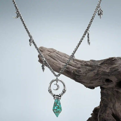 Silver Crescent Ward Necklace with turquoise spike pendant displayed on driftwood