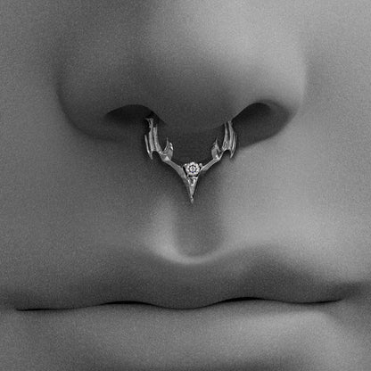 Close-up black and white shot of a nose wearing a silver-tone spiked septum ring with a clear gemstone