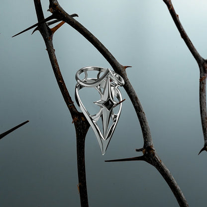 Silver-tone Crest Shield ring hanging from a dark thorn branch against a pale blue background