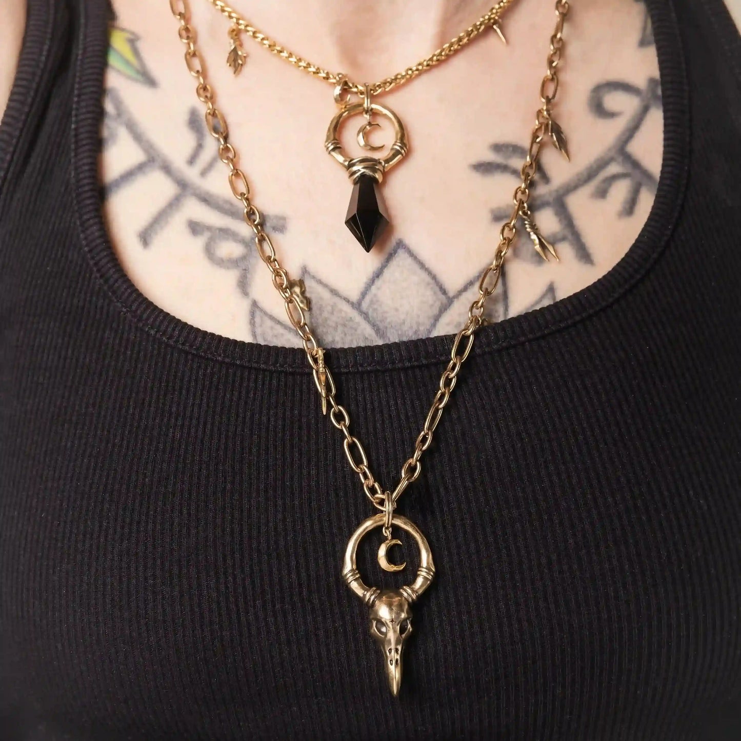 Model wearing the gold Crow Ward Necklace layered with dark gothic jewelry