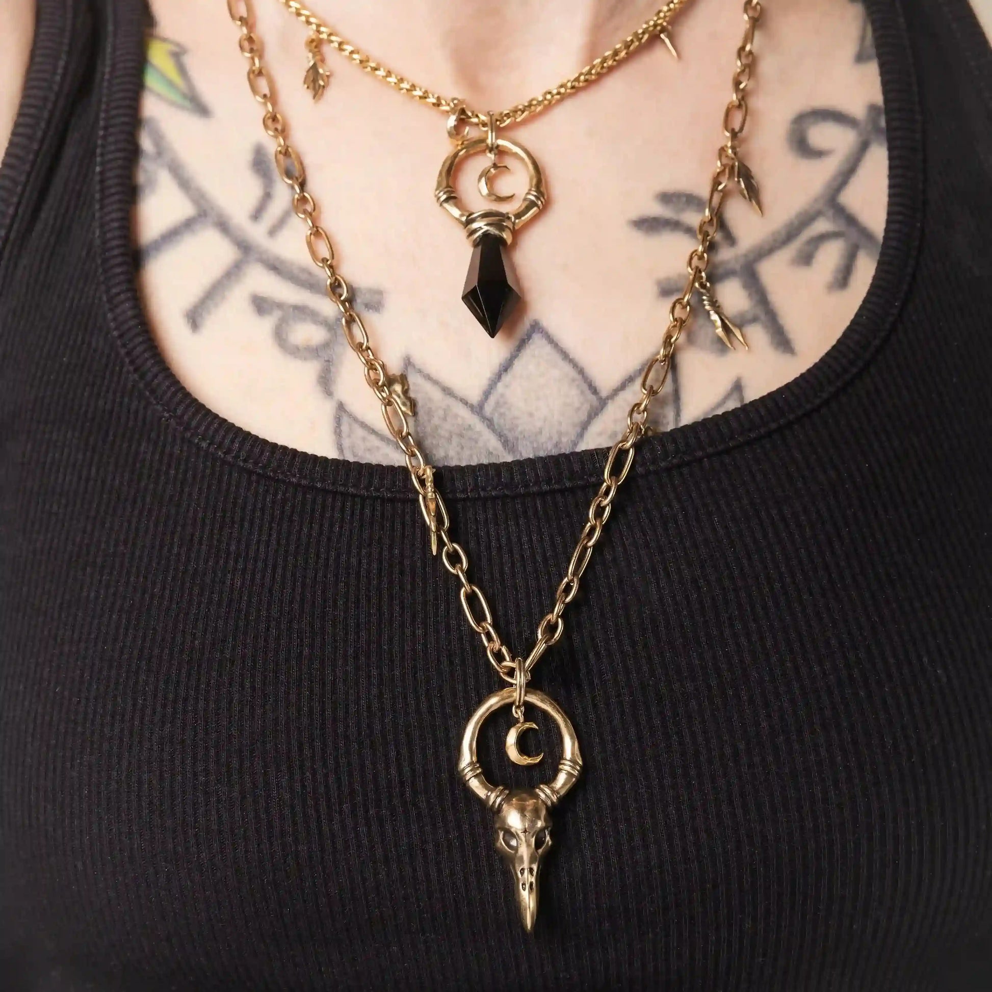 Model wearing the gold Crow Ward Necklace layered with dark gothic jewelry
