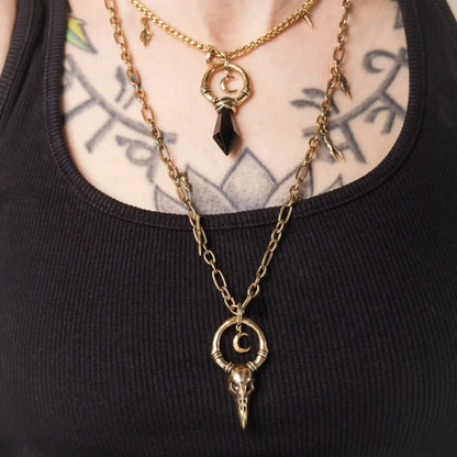 Model wearing the gold Crow Ward Necklace layered with dark gothic jewelry