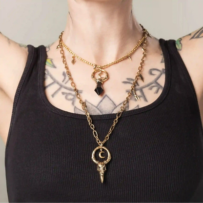 Gold Crow Ward Necklace styled on model with long bird skull pendant and charm details