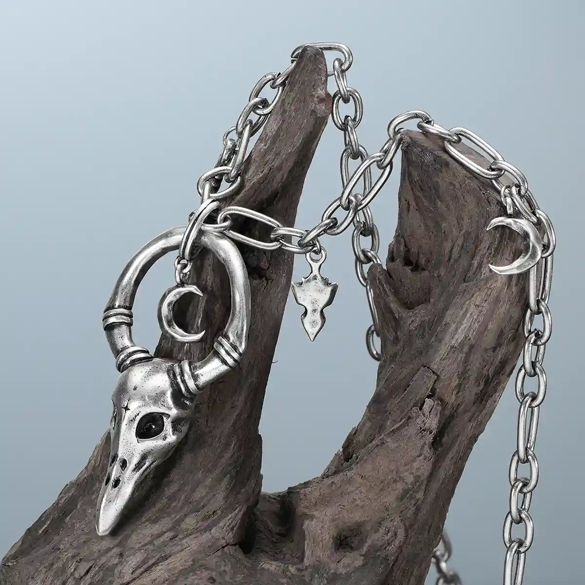 Silver Crow Ward Necklace hanging on weathered wood with antiqued crow skull pendant detail