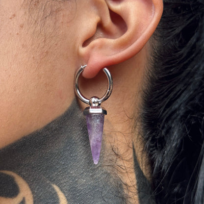 Silver-tone Crystal Prismatic hoop earring with a faceted purple crystal point worn on an earlobe