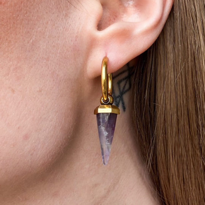 Close-up of a gold-tone Crystal Prismatic hoop earring with a tapered purple crystal pendant