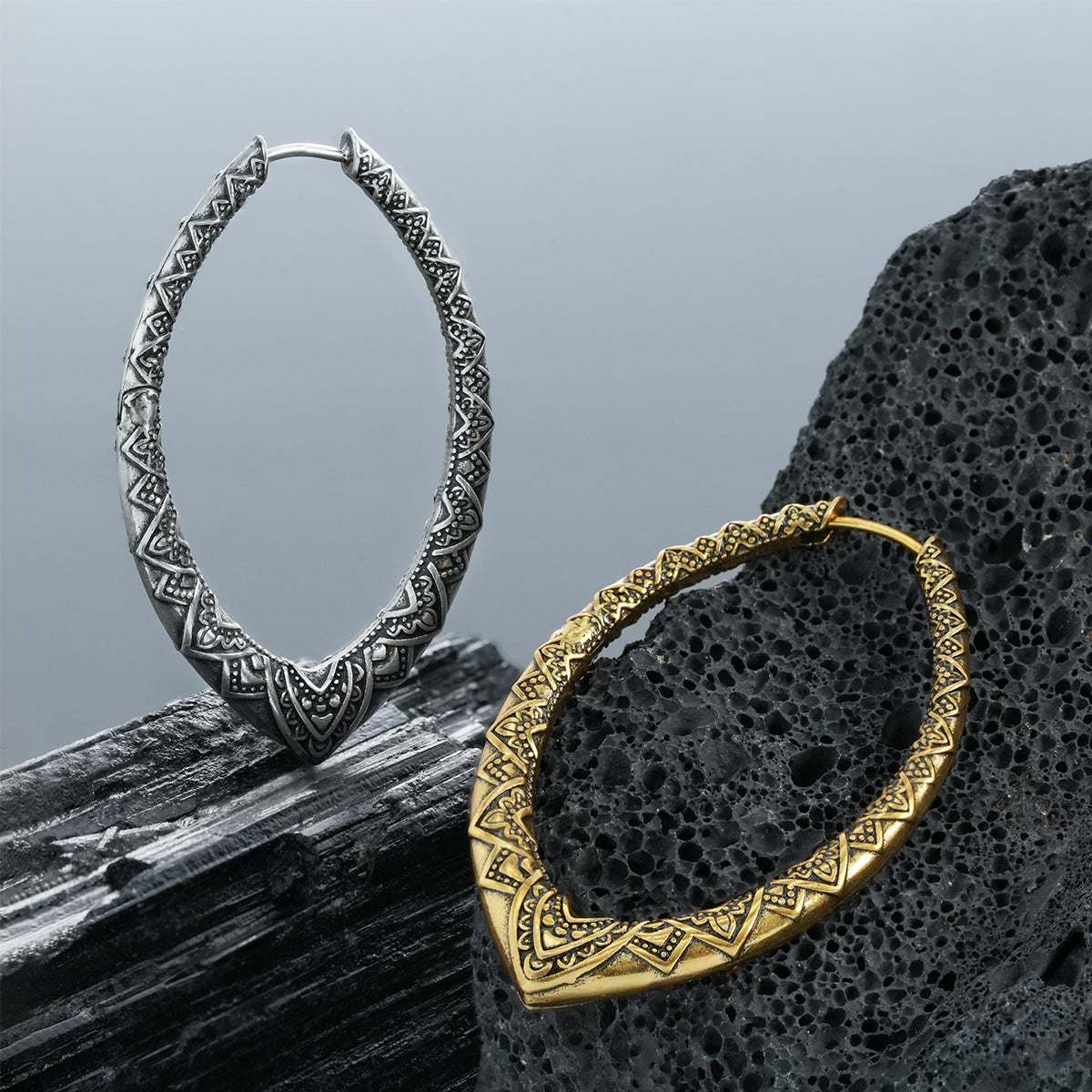Silver and gold Cultural Essence hoop earrings displayed on dark stone
