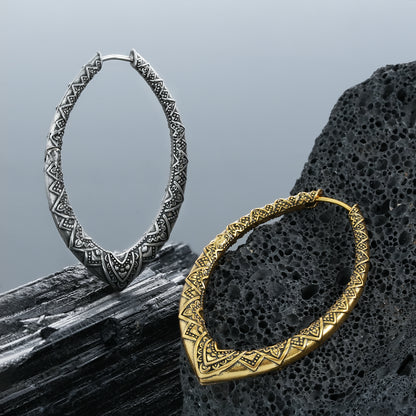 Silver and gold Cultural Essence hoop earrings arranged on dark rocks
